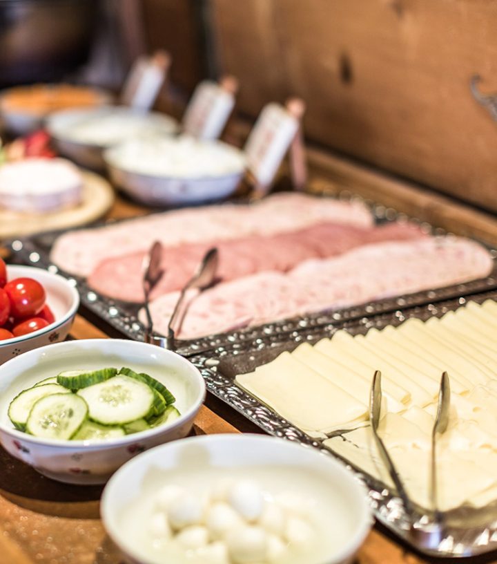 Ein reichhaltiges Frühstücksbuffet mit Wurst, Käse, Gurken, Tomaten und Mozzarella in Schalen.