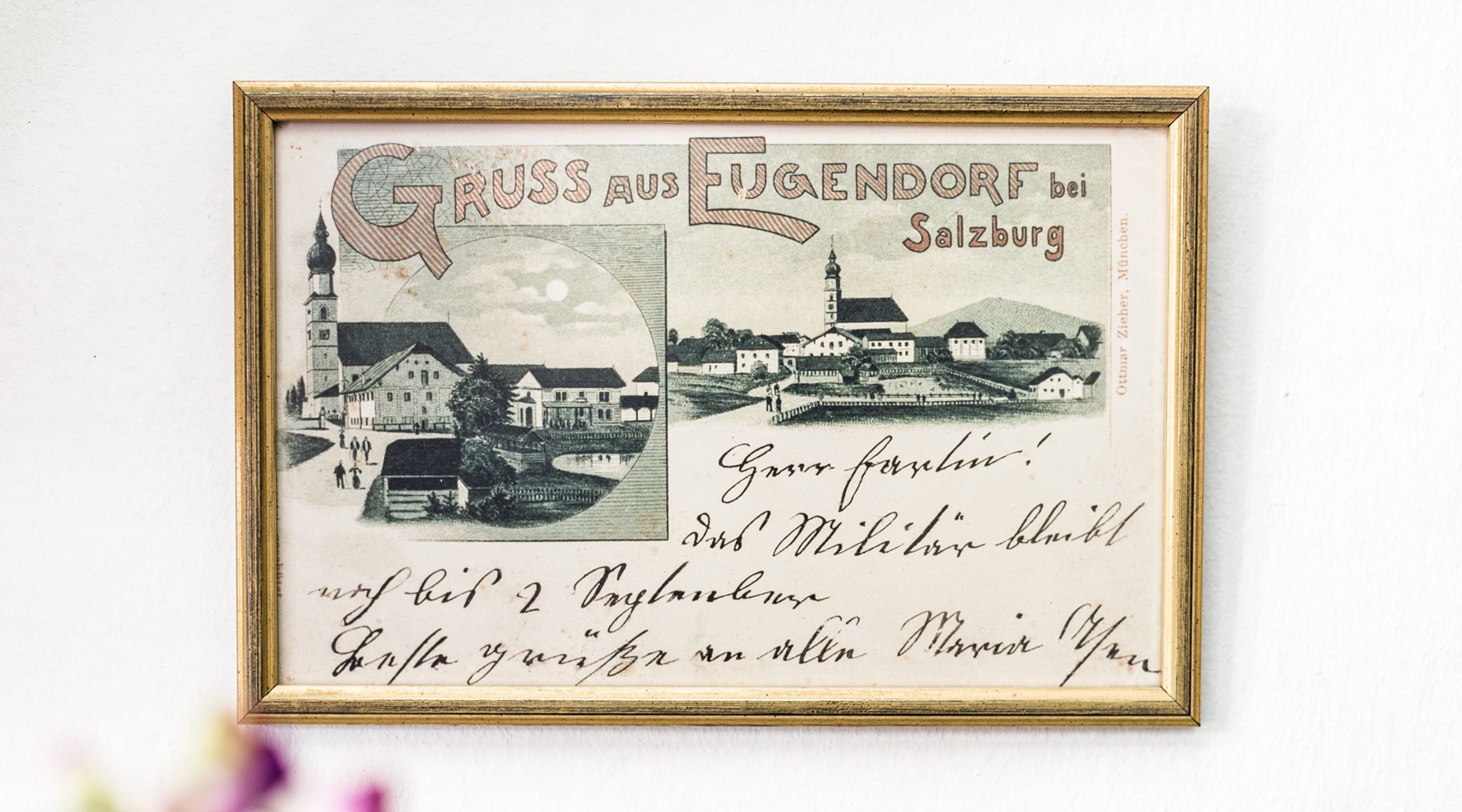 Historische Postkarte „Gruss aus Eugendorf bei Salzburg“ in goldenem Rahmen mit handschriftlichem Text.