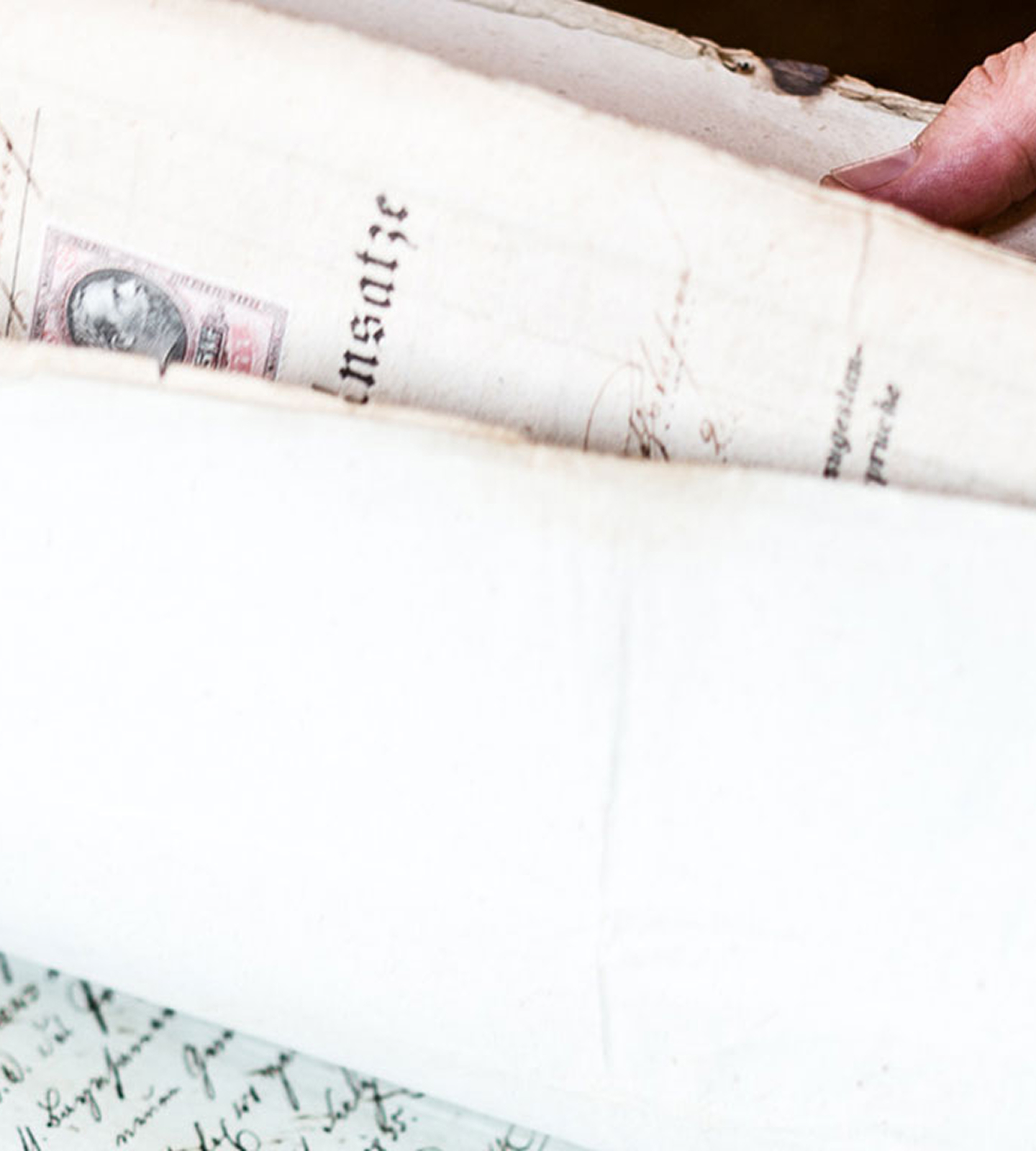 Ein Finger blättert in einem historischen Dokument mit der Aufschrift „Ansätze“ und einer Briefmarke.