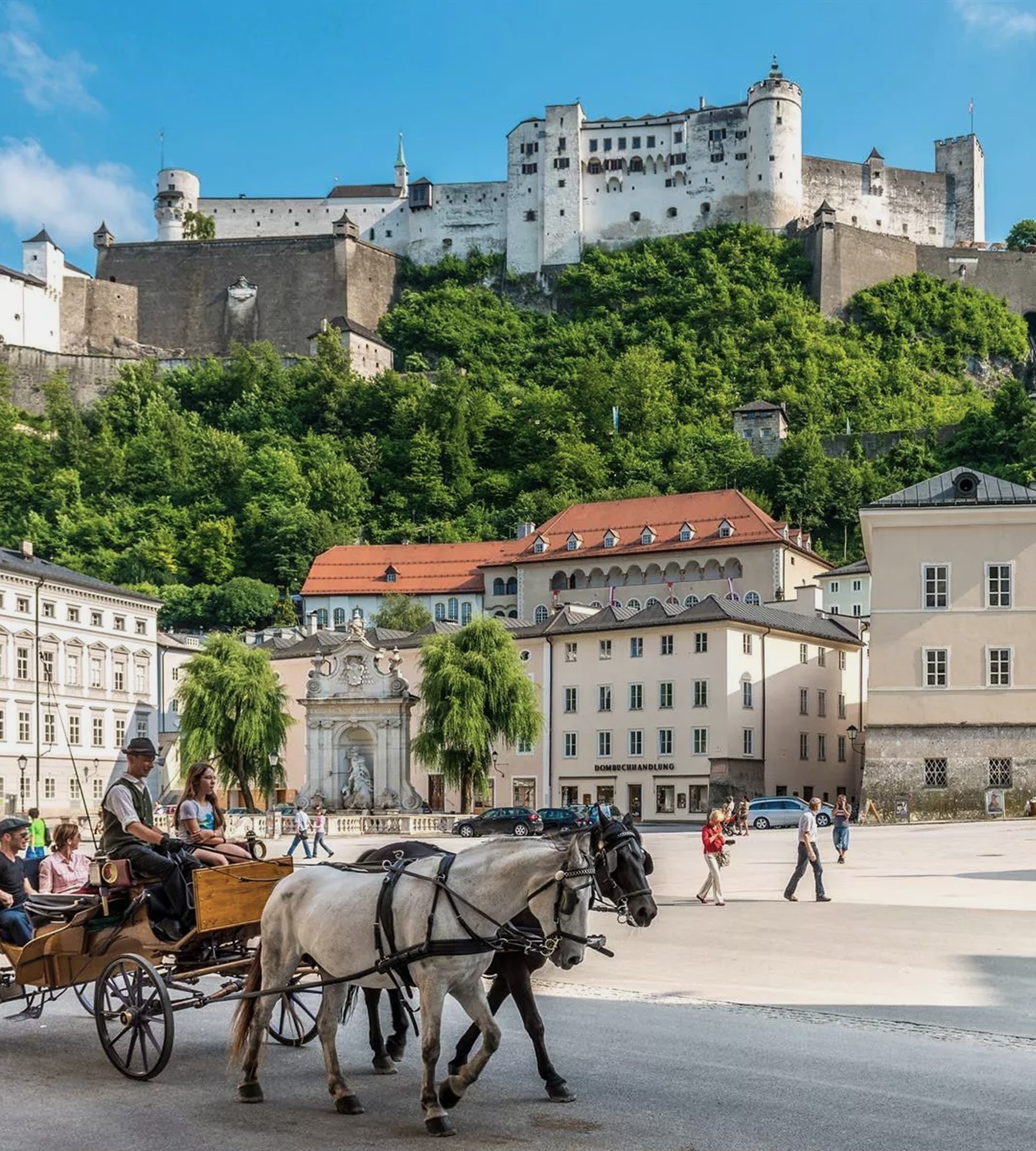 Pferdekutsche auf dem Kapitelplatz in Salzburg mit Blick auf die Festung Hohensalzburg im Hintergrund.