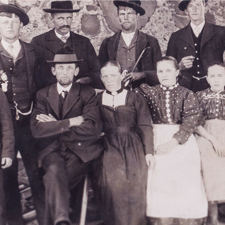 Historische Schwarz-Weiß-Fotografie einer Gruppe von Männern und Frauen in traditioneller Kleidung des 19. Jahrhunderts.