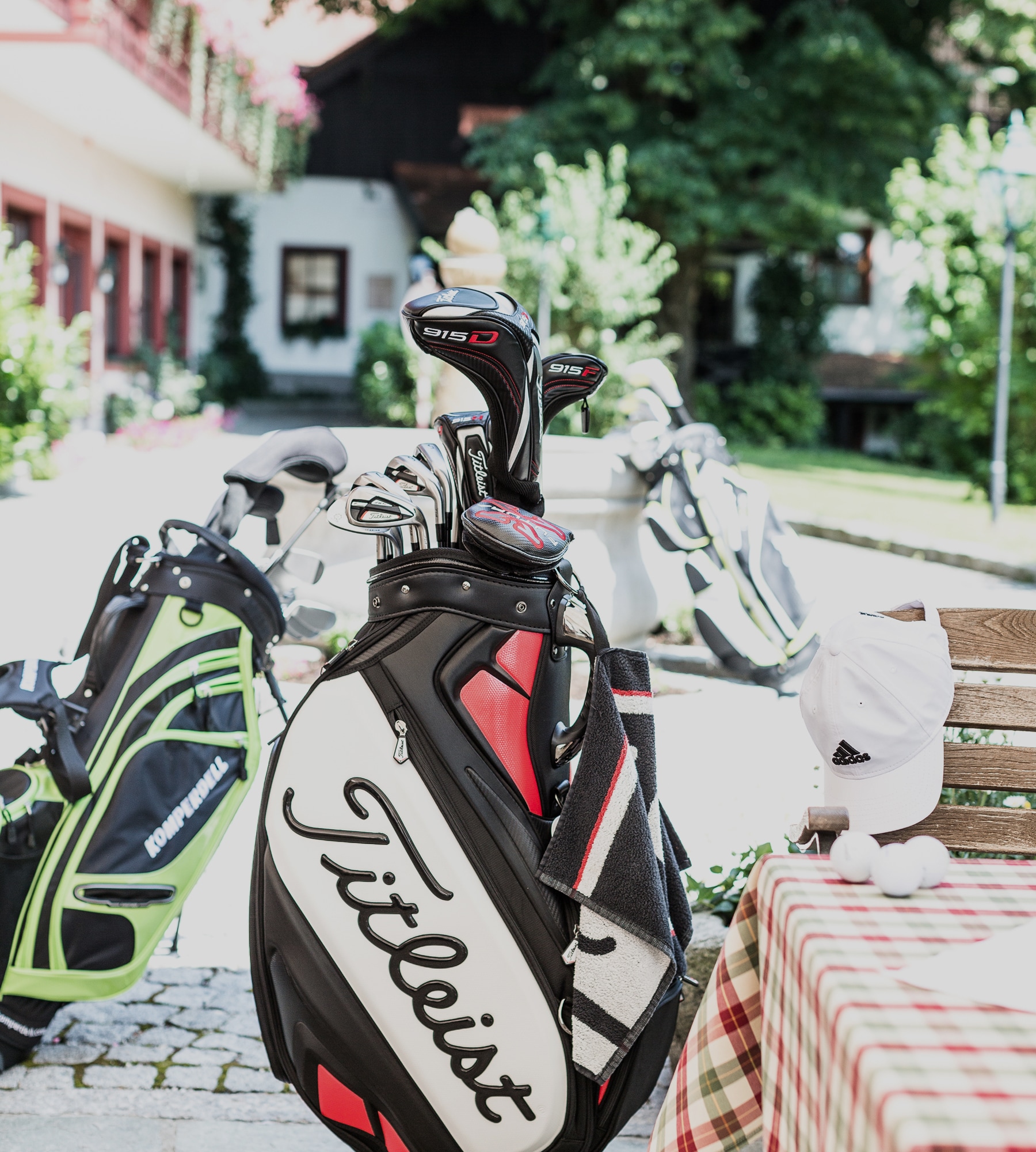 Eine schwarz-weiße Titleist-Golftasche mit Schlägern steht neben einem gedeckten Tisch im Freien.