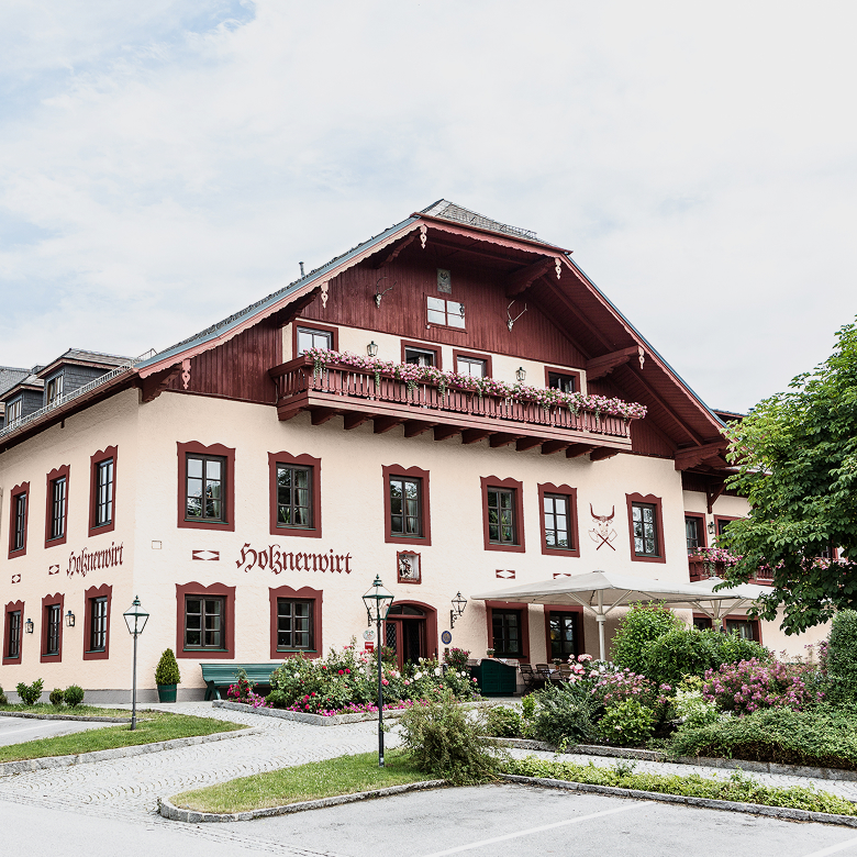 Der traditionelle Gasthof Holznerwirt mit blumengeschmücktem Balkon und gepflegtem Vorgarten.